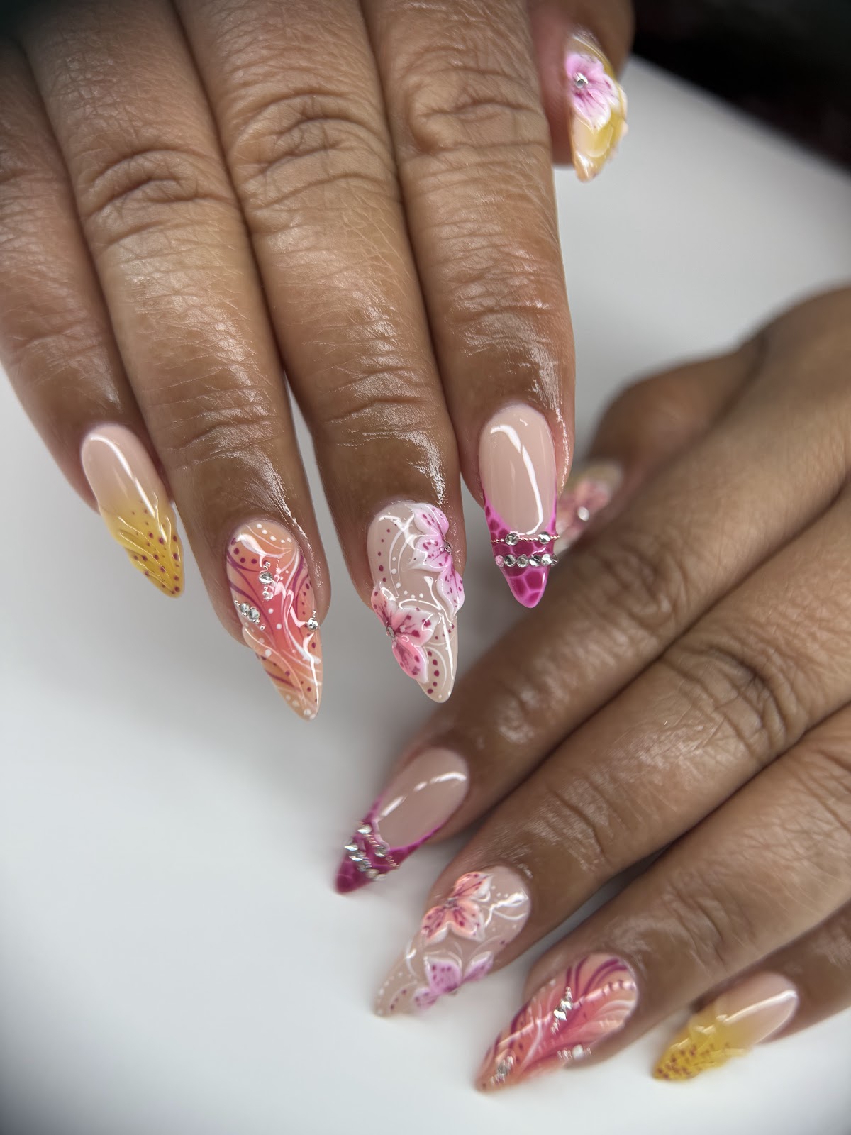 Tropical lily nail art with coral to yellow fades and rhinestone banding